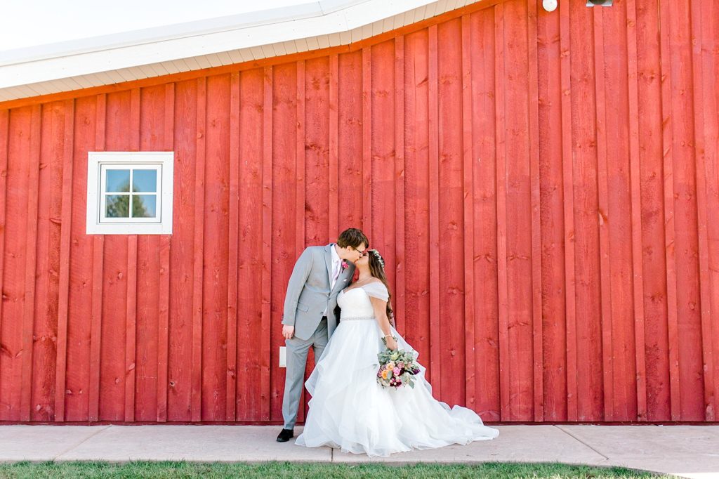 Almquist Farm wedding couple kissing in front of barn