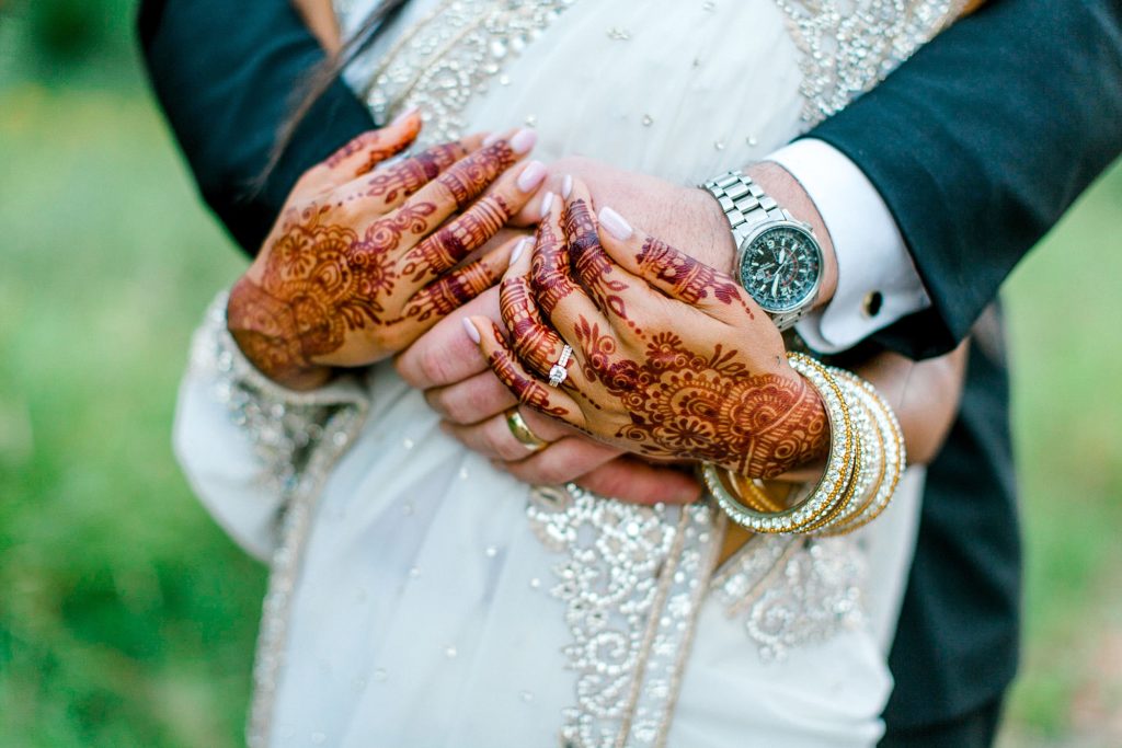 Bride and groom holding hands with Henna