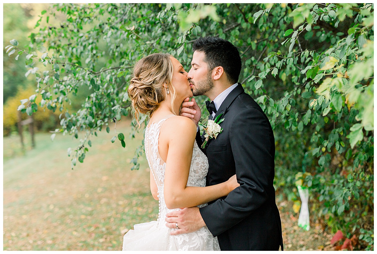 bride and groom kiss at autumn wedding