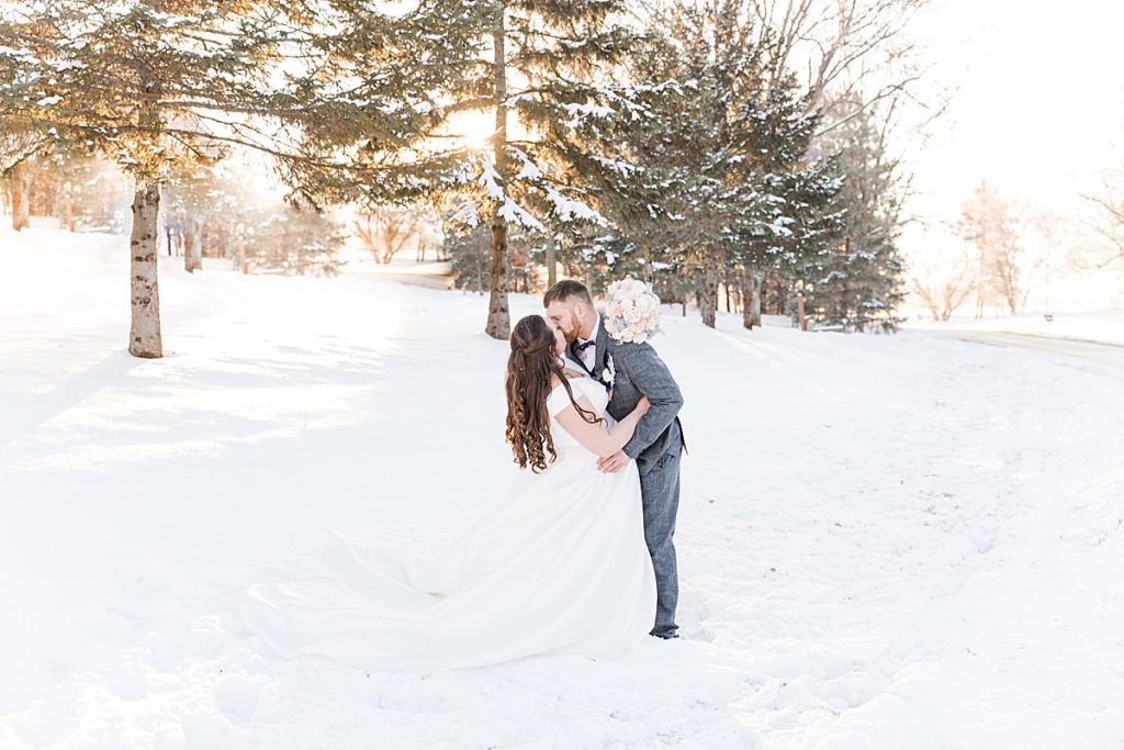 Bride and groom kissing in winter snow