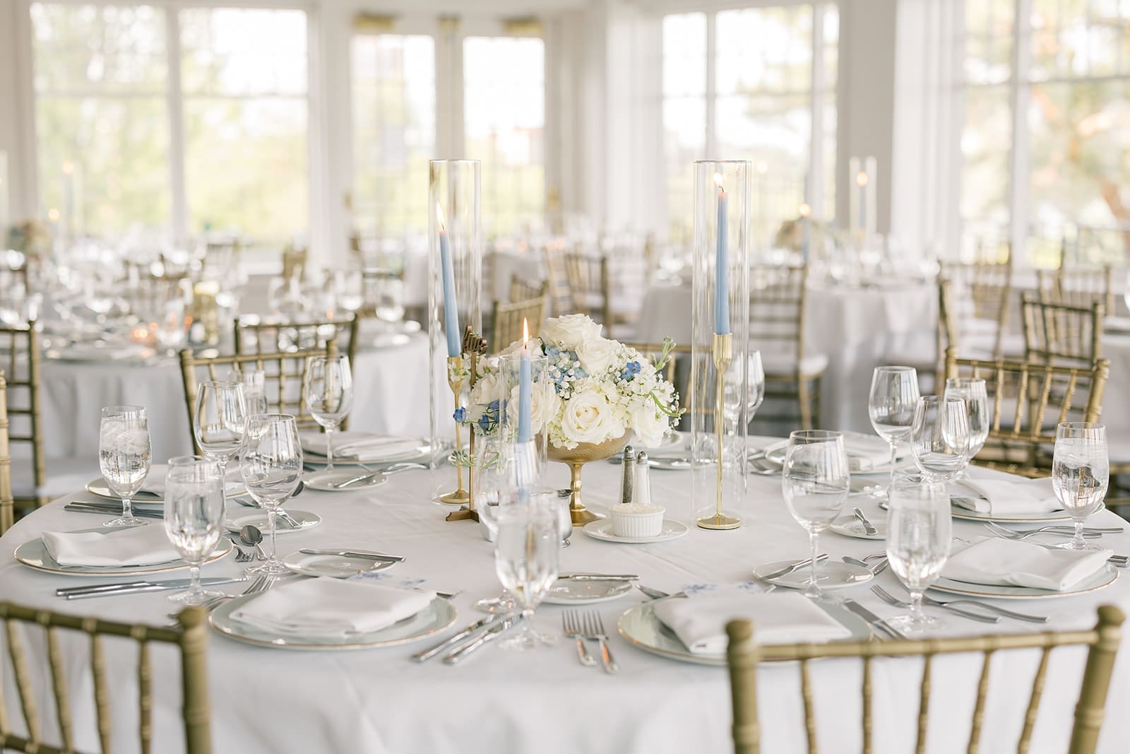 The Minikahda Club wedding reception tables with blue taper candles, white floral centerpieces, and gold chiavari chairs